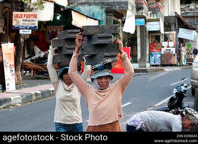 UBUD - 4 April 2011: woman working in construction carries very heavy stones on her head on April 4, 2011 on Ubud street on Bali, Indonesia