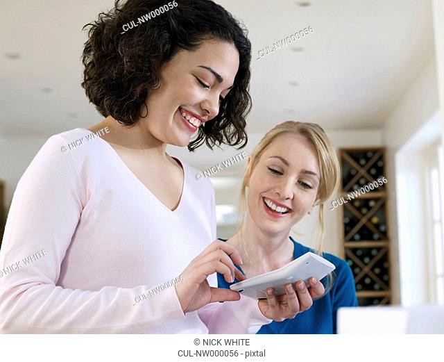 Two women using calculator at home