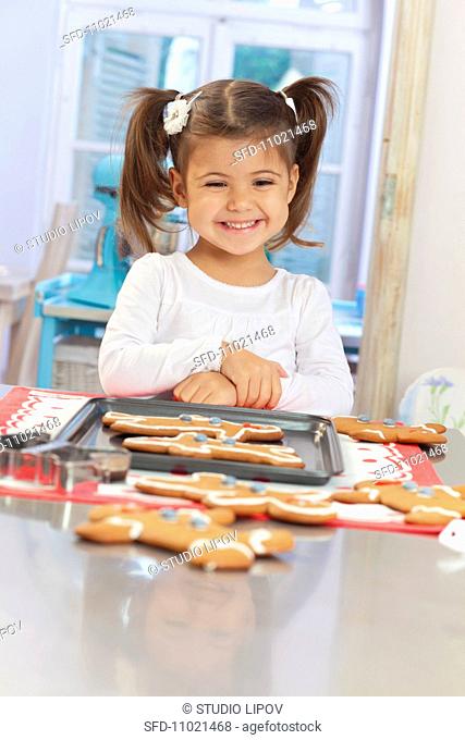 A little girl in front of a tray of gingerbread men