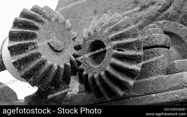 Two old stone gears with cobwebs that mesh in black and white