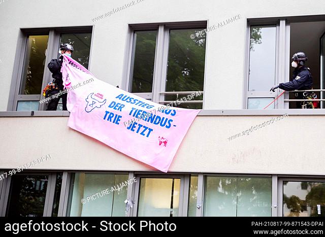 17 August 2021, Berlin: Police officers remove a banner from the façade of the German Farmers' Association during a blockade of the entrance to the building