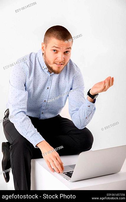 Confident young handsome man in shirt using laptop against white background