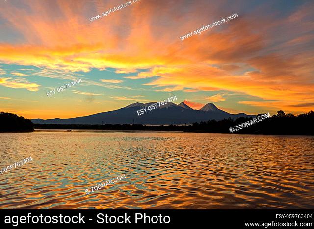 Beautiful sunrise over the volcanoes Kluchevskaya group with reflection in the river Kamchatka
