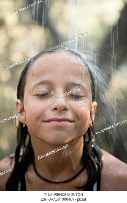 Girl under running water outdoors