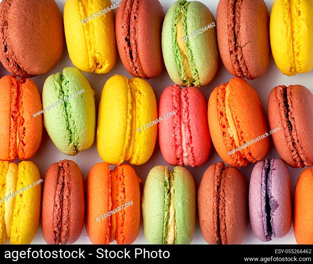round baked multicolored macarons lie in a row, full frame, bright almond cake, close up