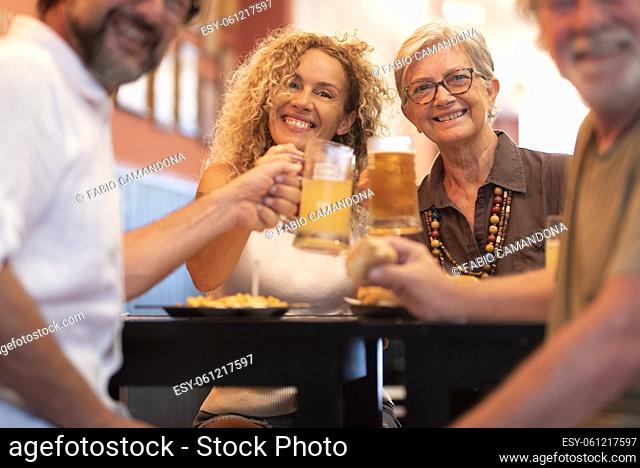 Happy cheerful family having fun and clinking beer glasses together while sitting at table in restaurant. Portrait of family toasting beer glasses and...