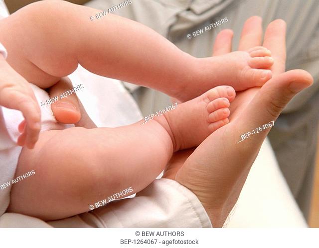 Mother' hand holding baby's feet