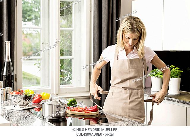 Mid adult woman tying apron in kitchen