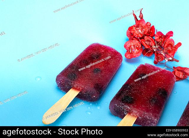Homemade healthy blueberry ice popsicle on fresh blue background, summer design with copy space colorful bright colors beauty