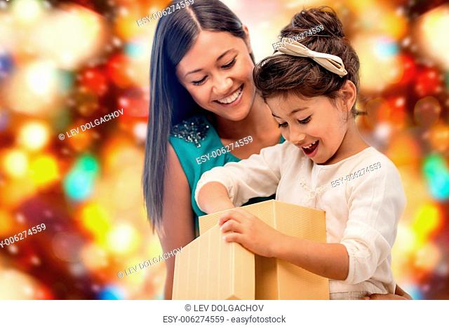 christmas, holidays, celebration, family and people concept - happy mother and child girl with gift box over red lights background