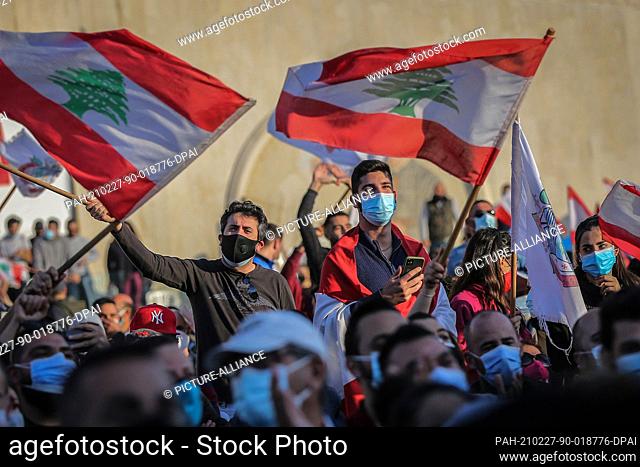 27 February 2021, Lebanon, Bkerki: Anti-government activists wave flags of Lebanon during a rally at the Maronite Catholic Patriarchate of Antioch of the...