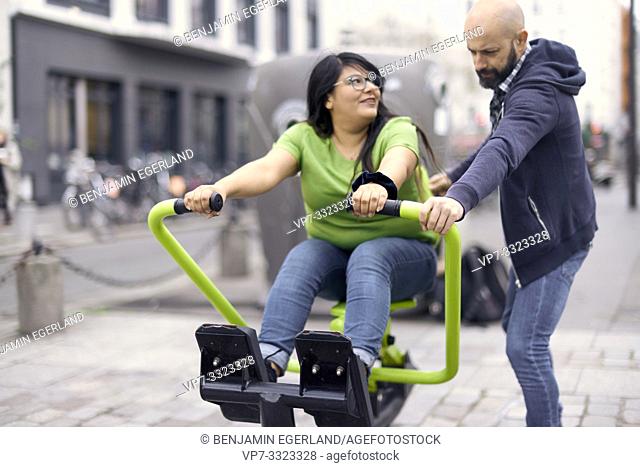man guiding woman on gym machine outdoors at public street, in Paris, France