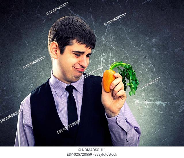 Small carrot in hand of a dissapointed man
