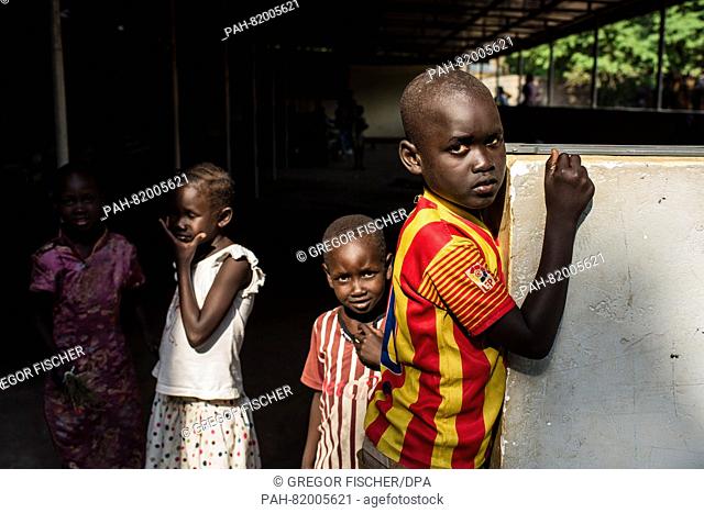 Children stand on the grounds of the St. Joseph Parish church, where they have sought shelter from the fights between the soldiers of the SPLA (Sudan People...