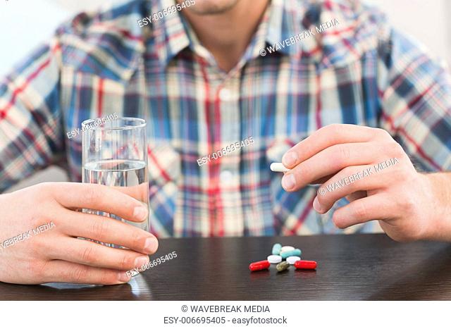 Casual man holding glass of water and tablet