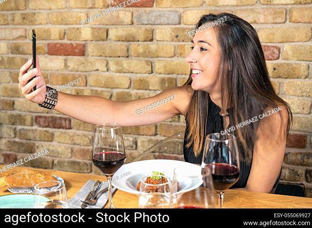 Beautiful Young woman is taking a selfie photograph while eating in restaurant. High quality photo