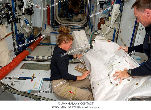 NASA astronauts Sandy Magnus, STS-135 mission specialist, and Chris Ferguson, commander, continue moving supplies and equipment