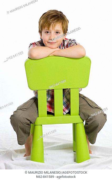 child sitting astride on a green chair