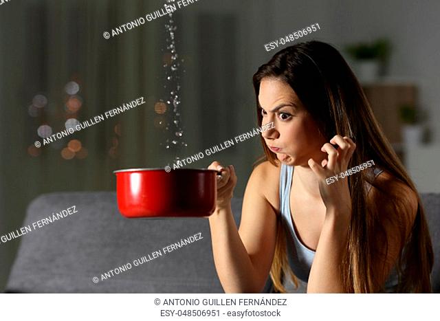 Angry woman having water leaks sitting on a couch in the living room at home