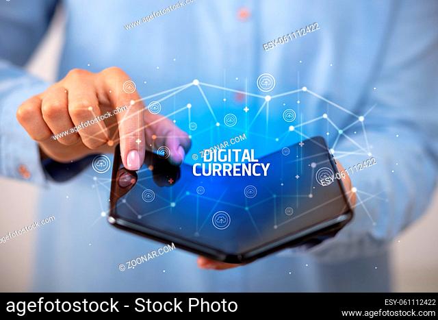 Businessman holding a foldable smartphone with DIGITAL CURRENCY inscription, new technology concept