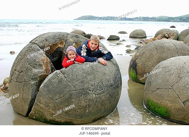 New Zealand - two children in crack of a Moeraki Boulder