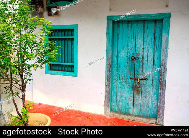 a House in George Town, Penang, Malaysia. Mediterranean style exterior. Blue wooden doors and window shutters on old painted wall