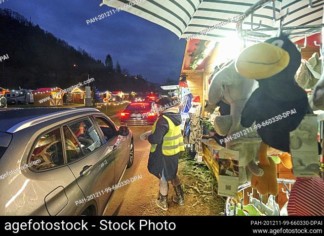 11 December 2020, Rhineland-Palatinate, Fachbach: A queue of cars drives past 15 Christmassy decorated cottages and stalls selling roasted almonds