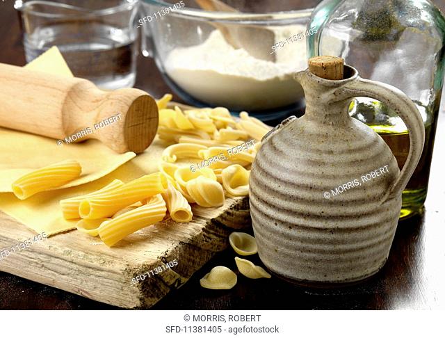Various types of dried pasta on a chopping board with ingredients