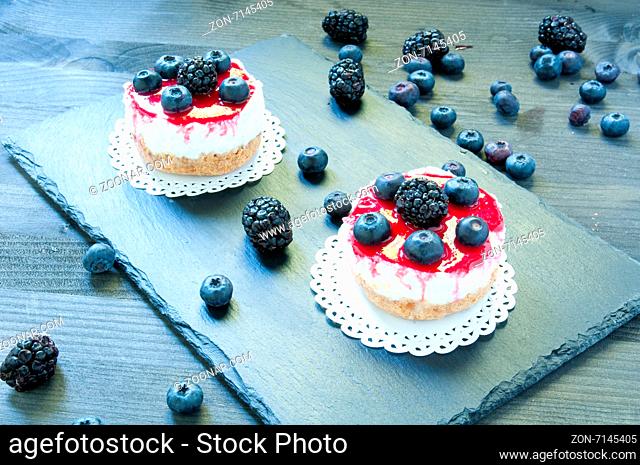 delicious strawberry cheese cake on a black plate with fresh blueberries in the background