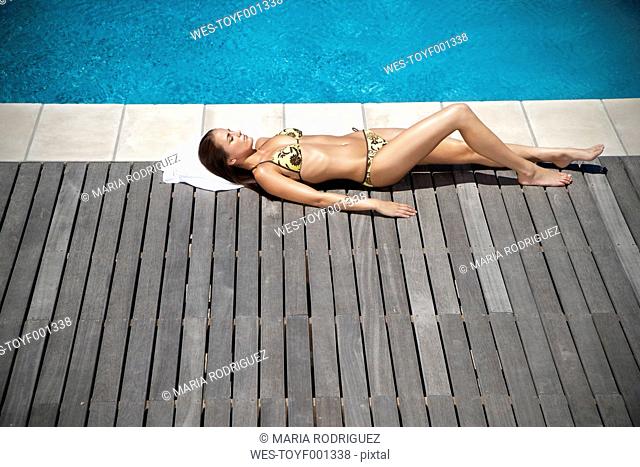 Young woman sunbathing at the poolside