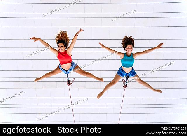 Aerial dancers with arms outstretched hanging on window