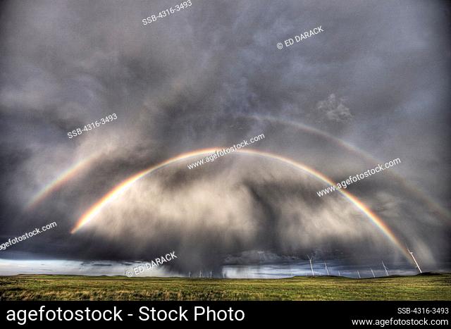 Double rainbow and thunderstorm over wind farm, high dynamic range, or HDR image