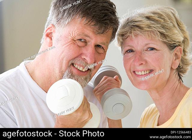 Portrait of a senior couple exercising with hand weights and smiling