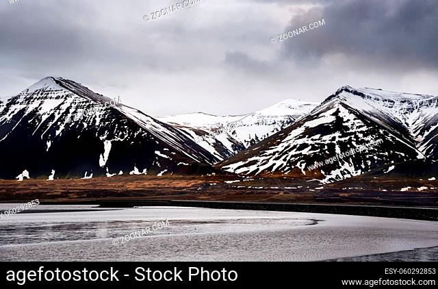 Icelandic landscape with frozen lake, snowcapped mountains and meadow land covered in snow at snaefellsnes peninsula in Iceland