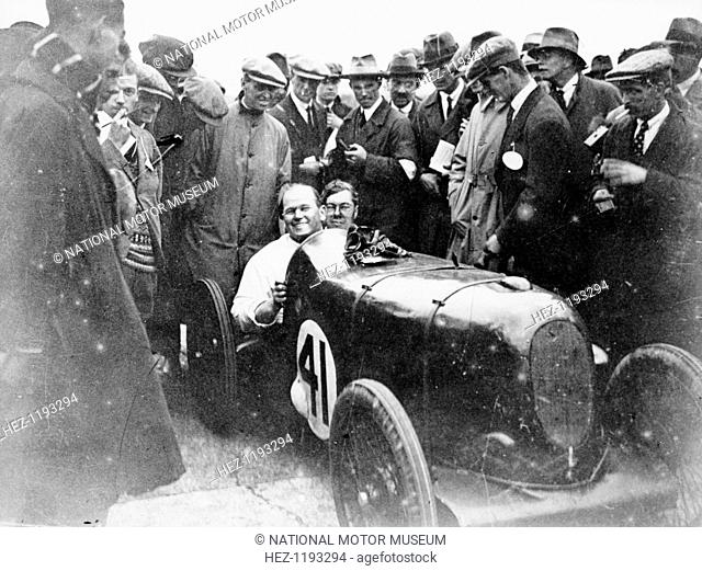 Gordon Taylor in a racing car surrounded by a crowd of men