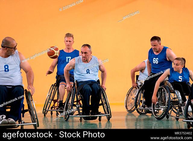 Disabled War veterans mixed race opposing basketball teams in wheelchairs photographed in action while playing an important match in a modern hall