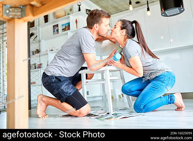 Junges Heimwerker Paar küsst sich beim Möbel aufarbeiten und Stuhl lackieren