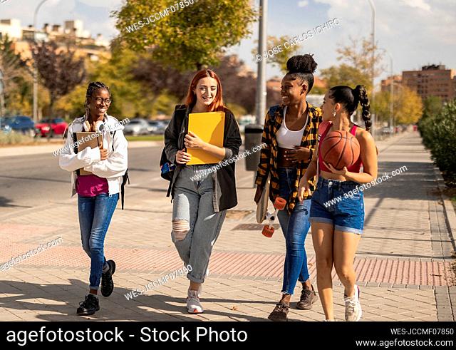 Young woman walking with friends on footpath