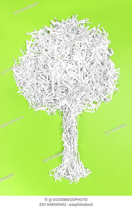 Tree made of shredded paper, on bright green background. Recycling and environment protection concept