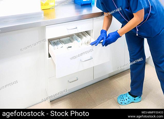 Mature nurse restocking medical supplies at hospital