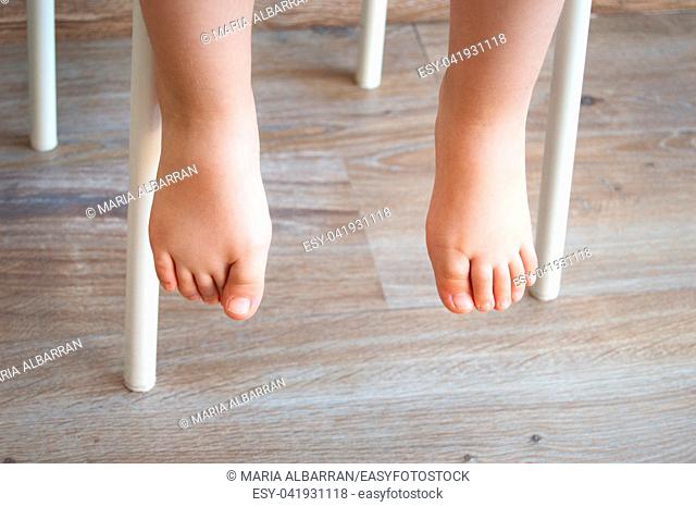 Feet of a child sitting in a chair. Natural lighting