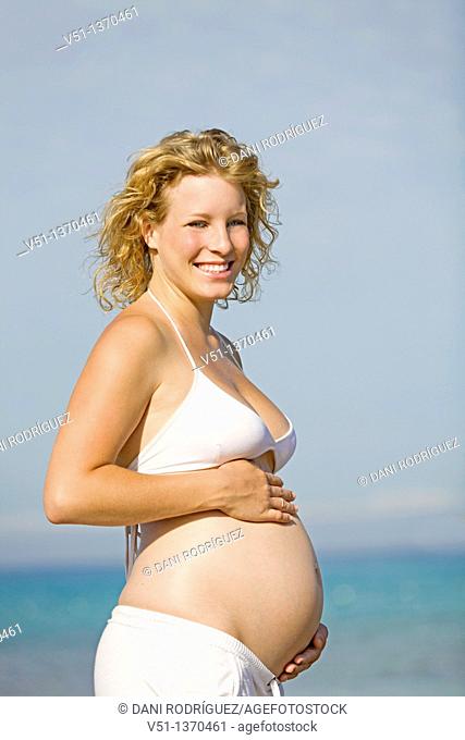 Blonde woman enjoying her pregnancy at the beach
