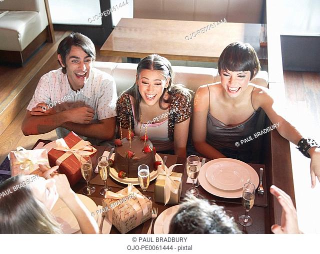 Five people talking and smiling at a birthday party in a restaurant