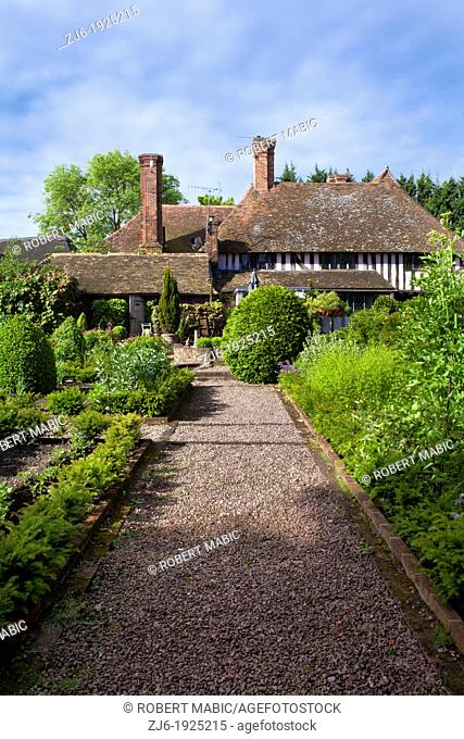 Gravel pathway through kitchen garden borders leading to the traditional Kentish house, Bexon Manor Kent England