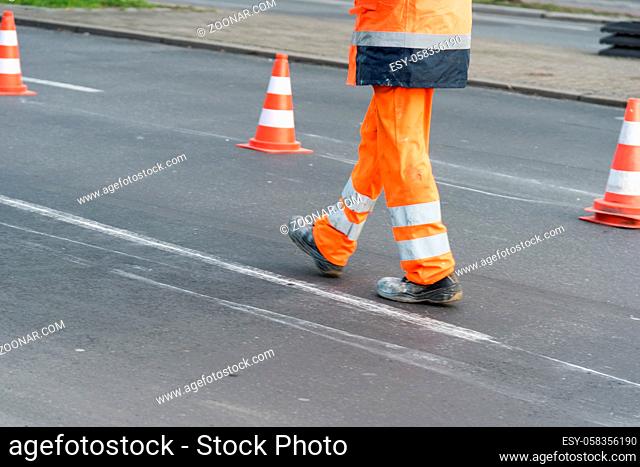 A road worker walks on the street with cones in the background