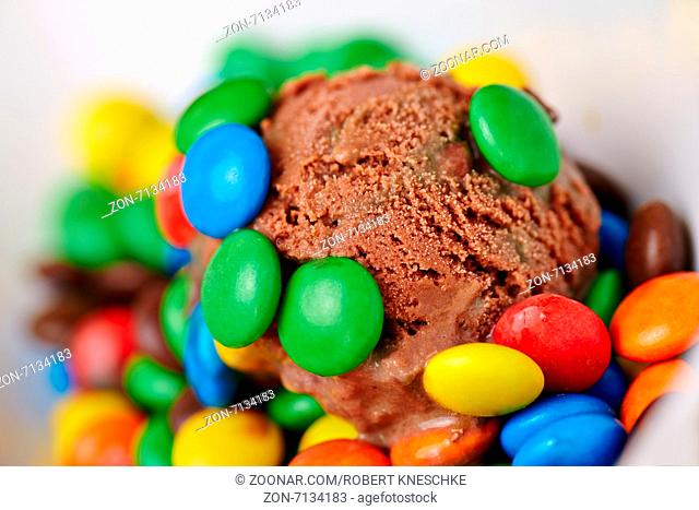 Eine Kugel Schokoladeneis mit vielen bunten Schokolinsen in einer Schale