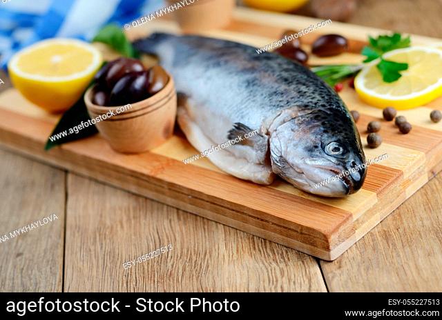 Raw trout on the chopping board with lemon and spices
