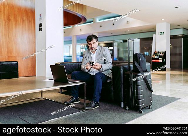 Male professional using mobile phone while sitting in hotel lobby