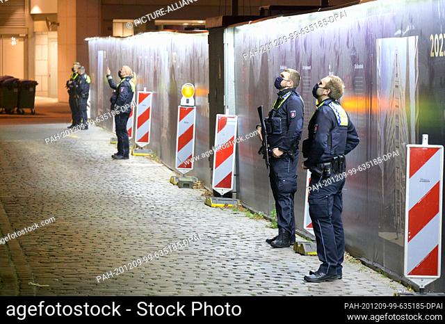 09 December 2020, Hamburg: Policemen stand with machine guns on a street and watch an office building. Because of a suspected armed robbery in Hamburg's city...