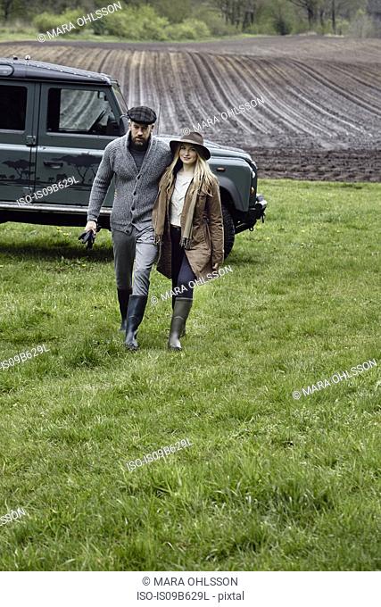 Country couple in outdoor clothes walking up field
